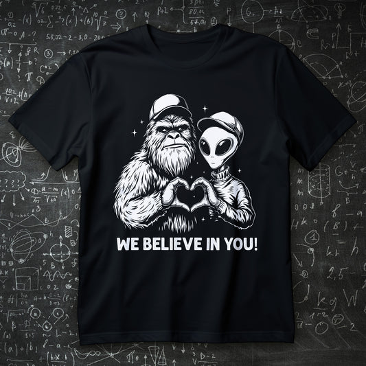 we believe in you t-shirt - bigfoot and alien making heart hands wholesome cryptid graphic
