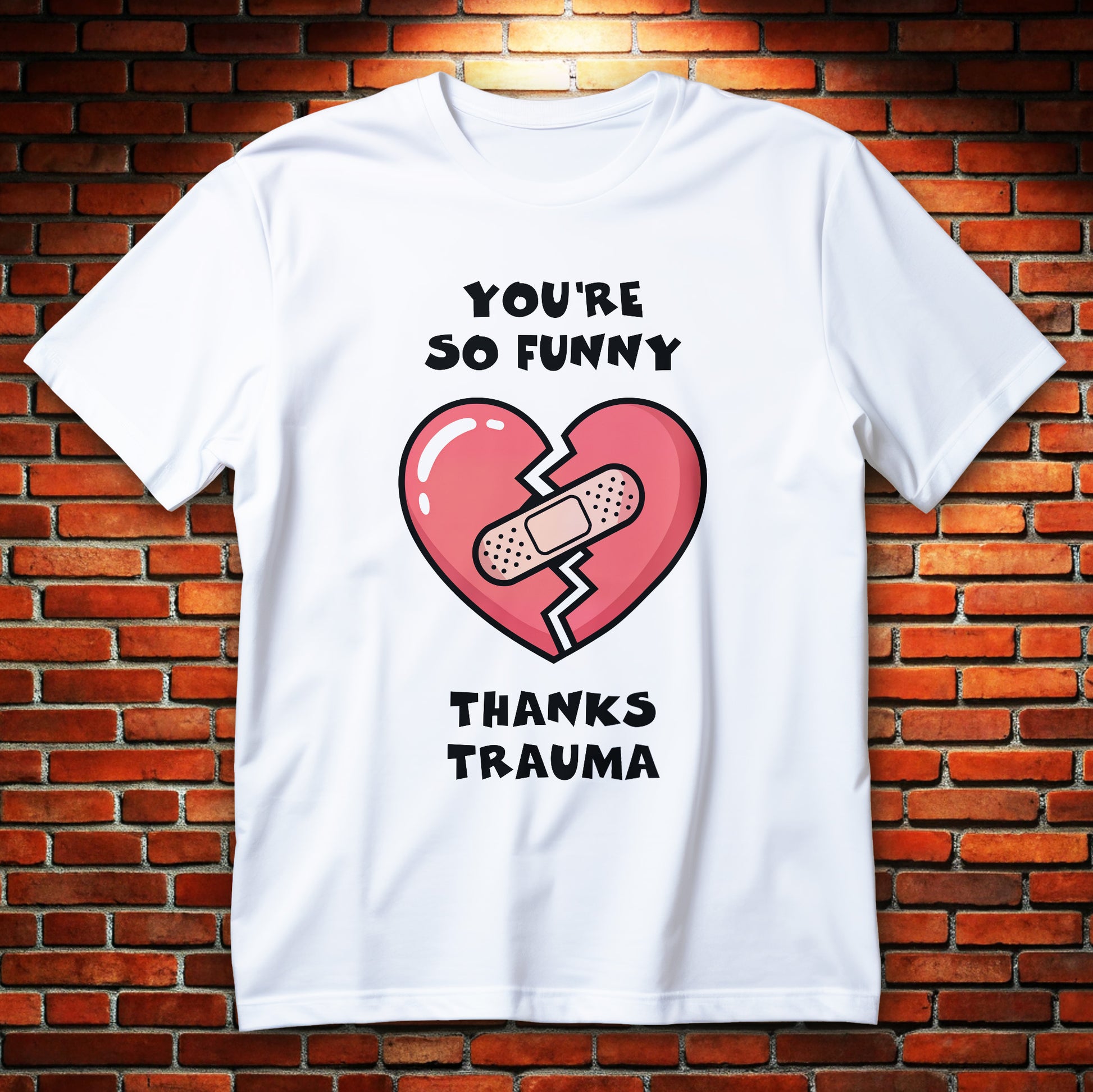 Cracked heart with bandage cartoon graphic and text “You’re So Funny Thanks Trauma” printed on a unisex T-shirt.