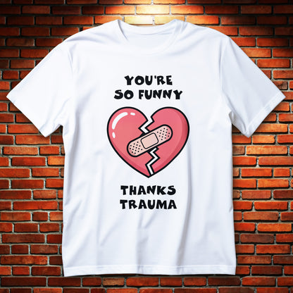 Cracked heart with bandage cartoon graphic and text “You’re So Funny Thanks Trauma” printed on a unisex T-shirt.